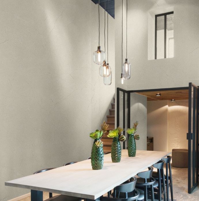 Long dining table below glass pendants against a plaster wall