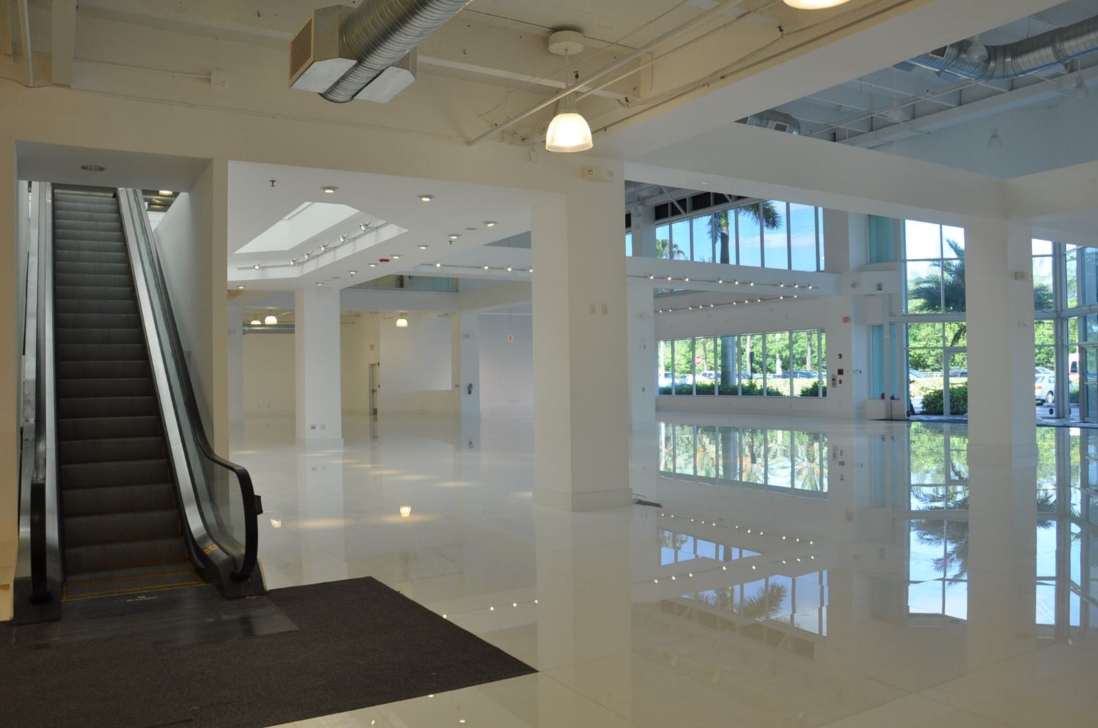 White entry hall with an escalator and a mirror-polished stone floor