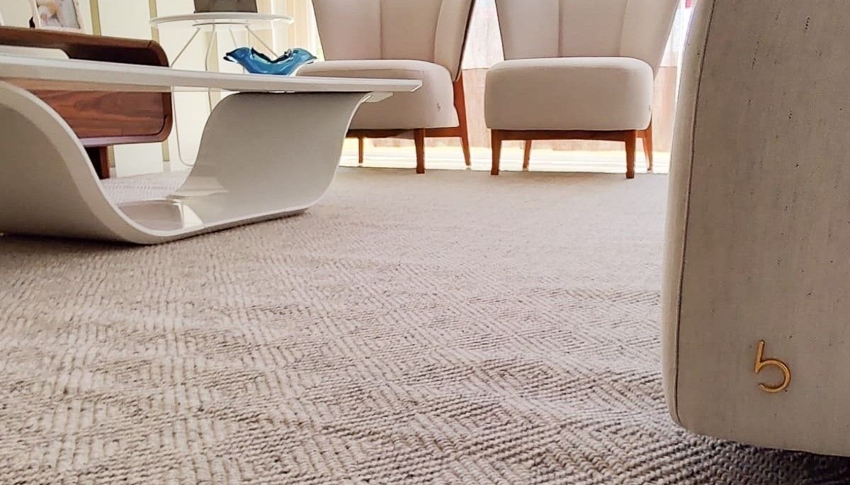 Herringbone wool rug under a sculptural white table, with a gold b mark on the sofa