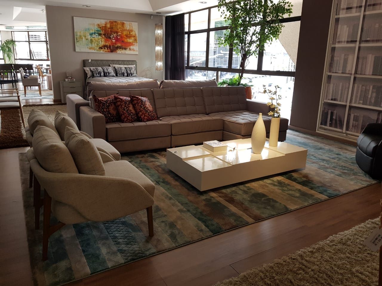 Rug striped in teal and rust laid between two seating groups on dark wood