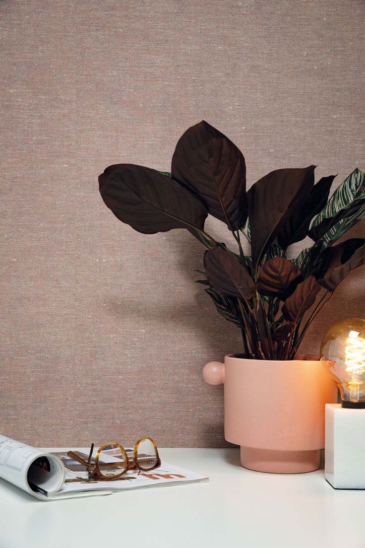 Blush grasscloth wall behind a plant and a lit candle
