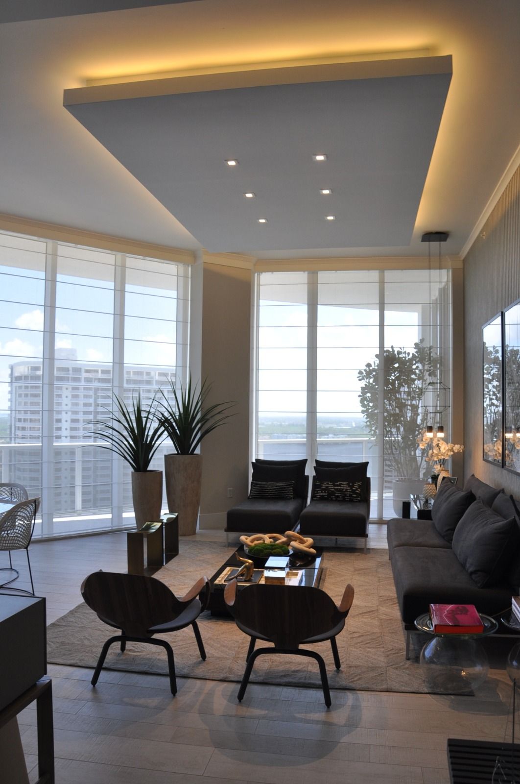 Corner living room where soft shades wrap floor-to-ceiling glass on two sides