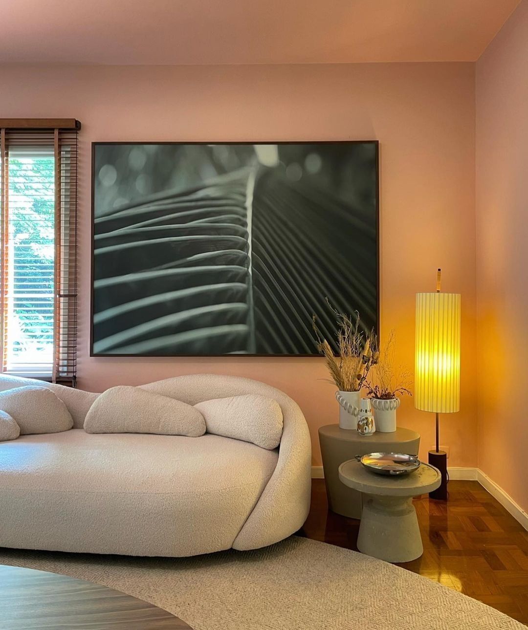 Living room with walnut wood blinds beside a curved sofa
