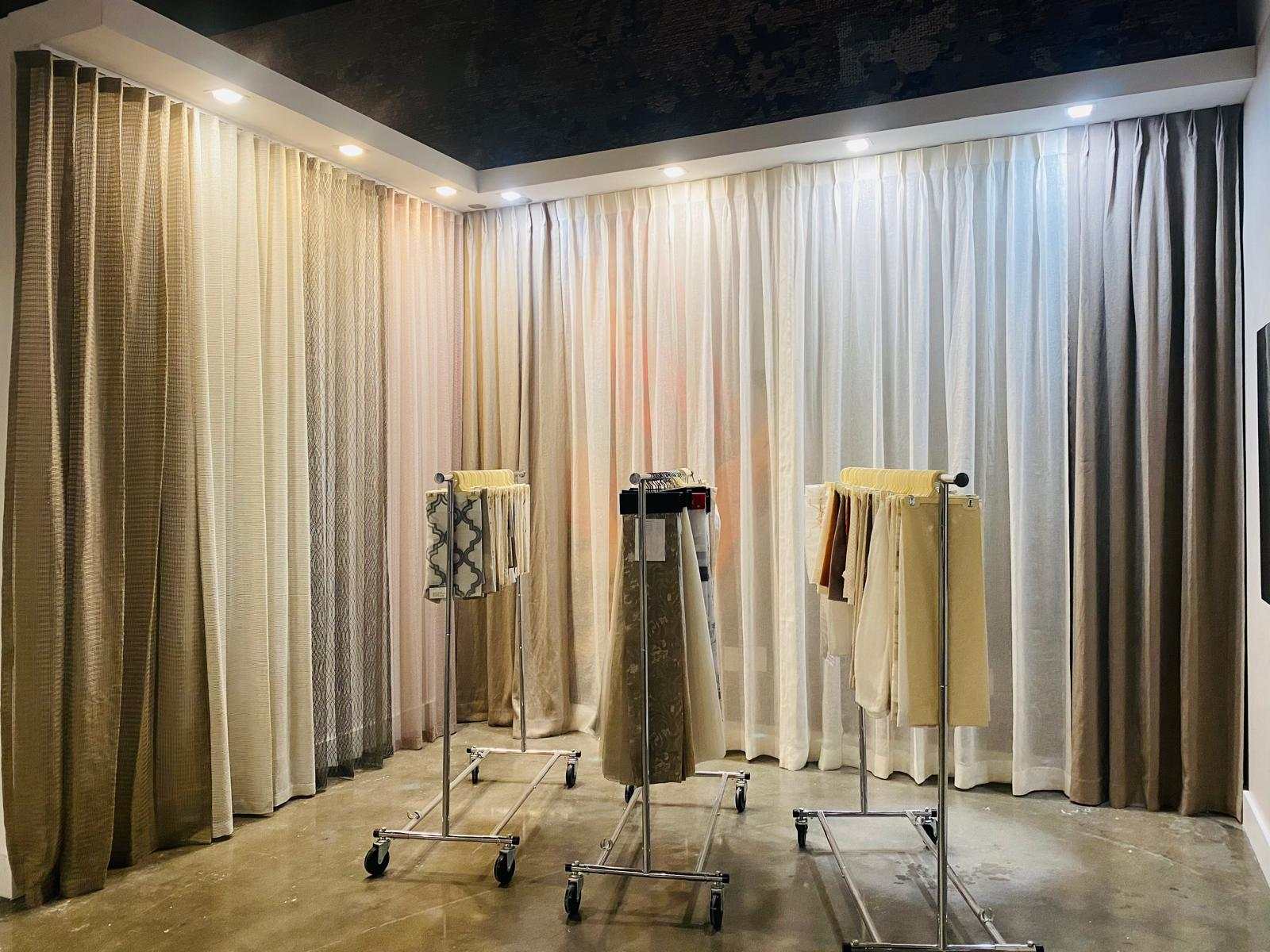 Bramstones showroom with floor-to-ceiling neutral drapery and rolling racks of fabric samples