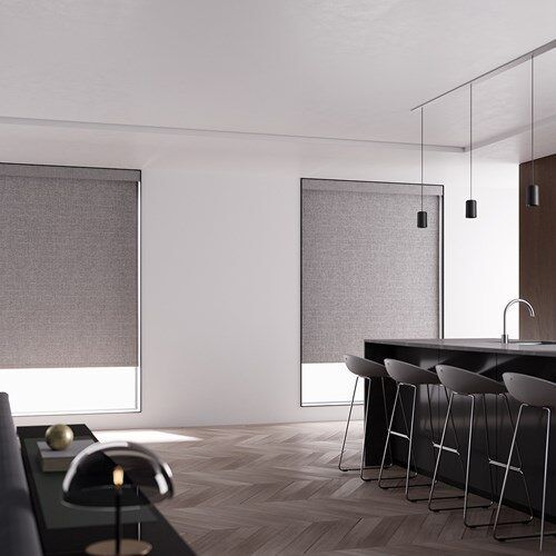 Pale roller shades over a kitchen counter and island