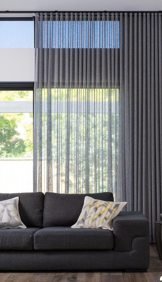 Grey sheer layered behind a solid drapery panel over a sofa