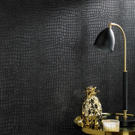 Black embossed reptile-pattern wall beside a brass lamp