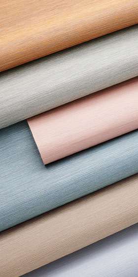 Rolls of finely striated vinyl wallcovering in muted sand, blue, blush and gray tones