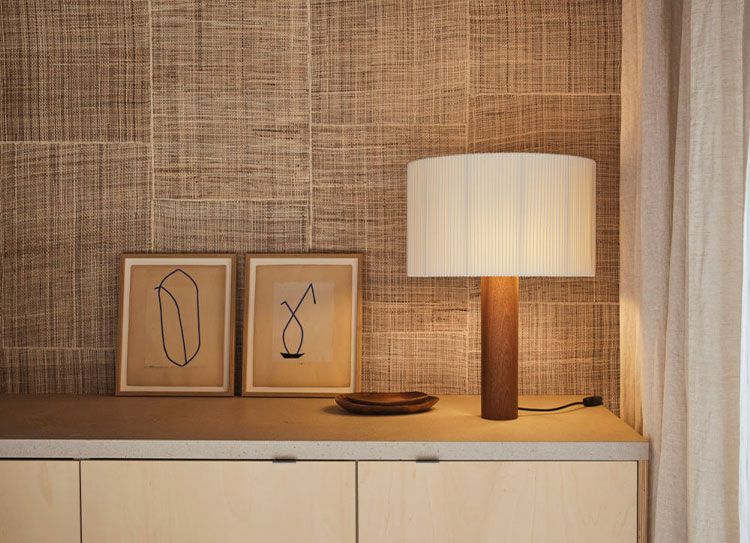 Natural woven wallcovering beside a warm table lamp